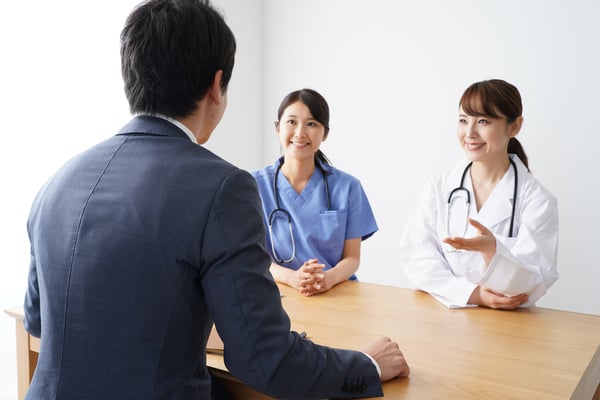 Image of physicians sitting with pharmaceutical representative